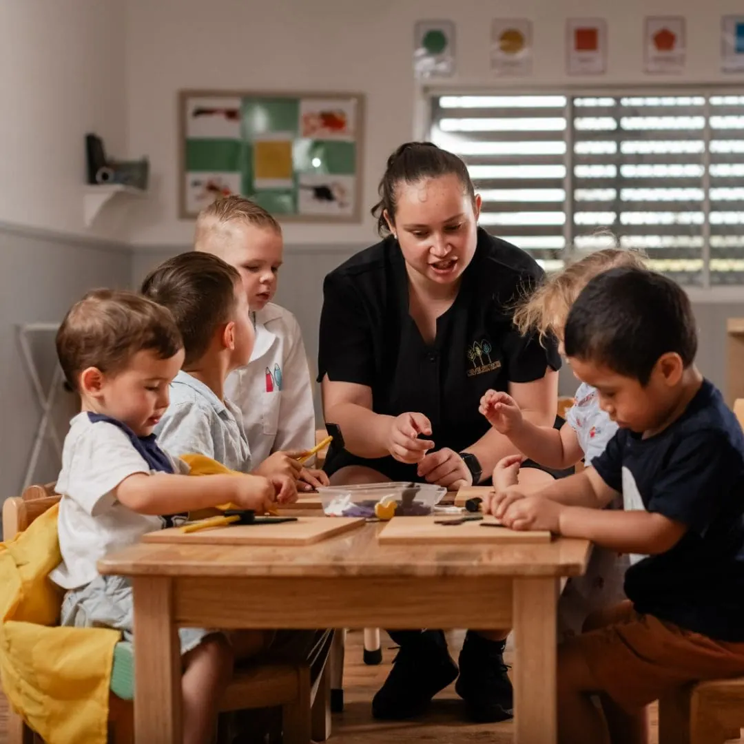 Children and their educator working together at a timber table inside the Eagleby studio