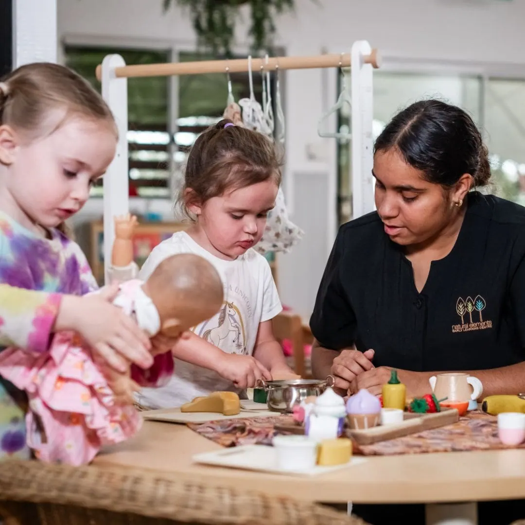 Indoor dining and dramatic play room with timber furniture and natural light at Natural Elements Eagleby
