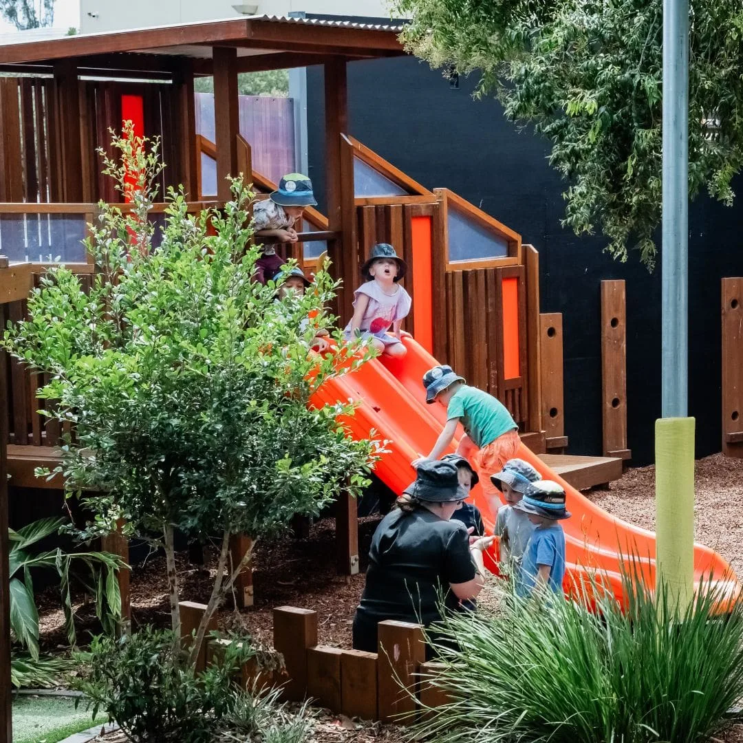 Children climbing and sliding on the fort amongst the gardens