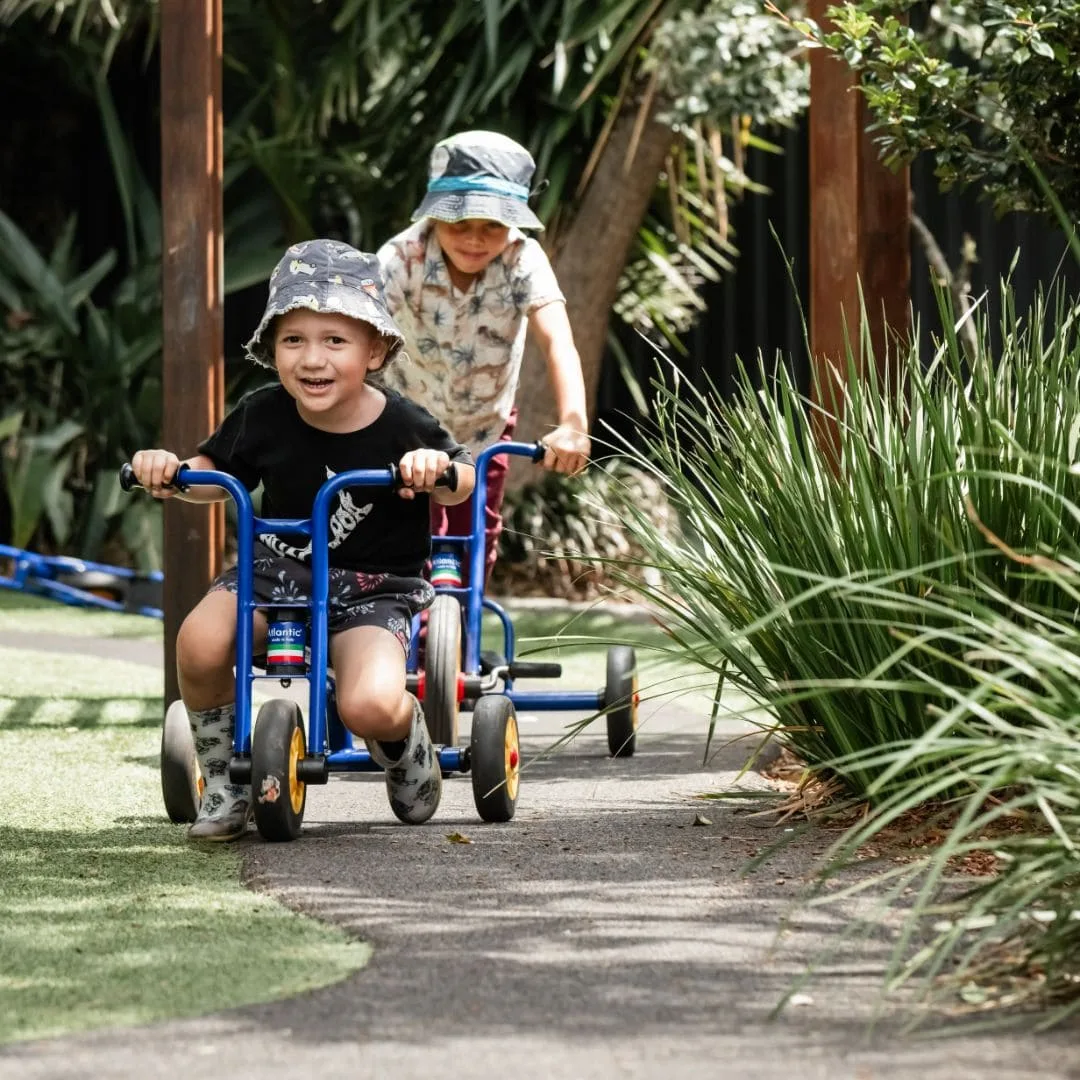 Children riding trikes together along the garden path