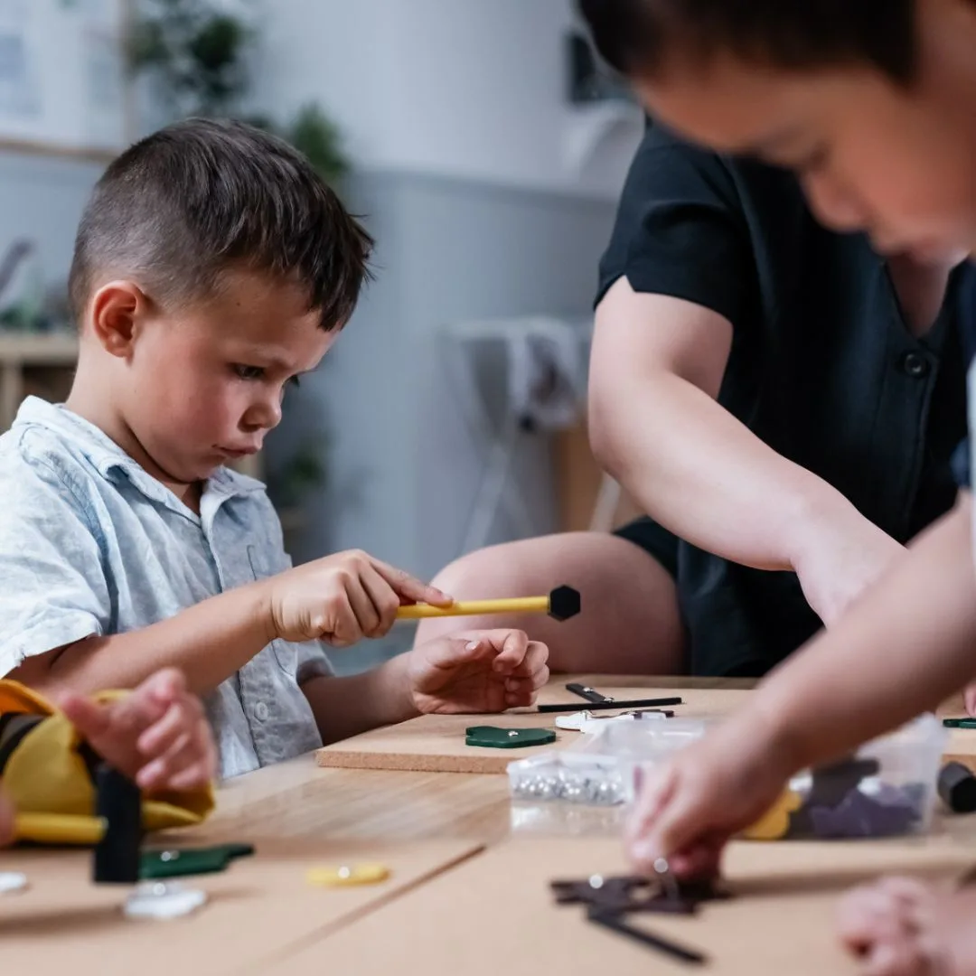 Child learning to use real tools at the woodwork table